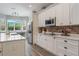 Well-lit kitchen with white cabinetry, stainless appliances, brick backsplash and ample counter space by the window at 10100 Loblolly Pine Cir, Orlando, FL 32827