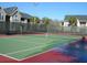 Community tennis court with green and red surface, enclosed by a black fence and palm trees at 1051 S Hiawassee Rd # 2136, Orlando, FL 32835