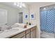 Bright bathroom featuring a double vanity with a quartz countertop and a shower with blue decorative curtains at 1221 Aloha Blvd, Davenport, FL 33897