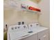 Bright laundry room featuring a new white washer and dryer with overhead shelving for extra storage at 1221 Aloha Blvd, Davenport, FL 33897