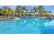 Large community pool surrounded by sun loungers, umbrellas, and tropical landscaping on a sunny day at 1221 Aloha Blvd, Davenport, FL 33897