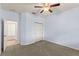 Carpeted bedroom with neutral walls, a ceiling fan, closet doors and an open doorway to another room at 12691 Calderdale Ave, Windermere, FL 34786