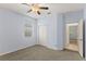 Carpeted bedroom with neutral walls, a ceiling fan, closet doors, a window and an open doorway at 12691 Calderdale Ave, Windermere, FL 34786