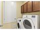 Laundry room featuring a front loading washer and dryer and wood cabinets for storage at 12691 Calderdale Ave, Windermere, FL 34786