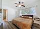 Cozy bedroom with a ceiling fan, wood floors, and a view to the ensuite bathroom at 2114 Mount Vernon St, Orlando, FL 32803