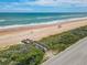 A wooden boardwalk leading to a sandy beach with a colorful sun umbrella under a partly cloudy sky at 3100 Ocean Shore Blvd # 4030, Ormond Beach, FL 32176