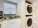 Bright kitchen area featuring a stainless steel sink beneath a window and an in-unit washer and dryer at 3100 Ocean Shore Blvd # 4030, Ormond Beach, FL 32176