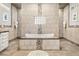 Luxurious bathroom with stone tile, mosaic accents, and a soaking tub with a privacy glass block window at 40137 County Road 452, Leesburg, FL 34788