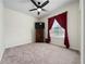 A well-lit bedroom with neutral carpeting, a ceiling fan, and a window with red curtains at 426 Citrus Isle Loop, Davenport, FL 33837