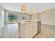 Open kitchen view showing island with sink, stainless steel dishwasher, and pendant lights over grey wood-look floors at 5215 Nw 34Th St, Ocala, FL 34482