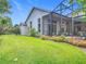 A beautiful backyard featuring lush lawn, well-kept landscaping, and a screened-in patio with outdoor seating at 600 Garden Club Dr, Deland, FL 32724