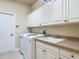 Bright laundry room with sink, white cabinets, and modern washer and dryer at 600 Garden Club Dr, Deland, FL 32724