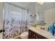 Well-lit bathroom features a vanity, toilet, shower and patterned shower curtain for added visual appeal at 6017 Brookhill Ct, Orlando, FL 32810