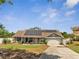 Charming single-story home with a well-manicured lawn, solar panels, and attached two-car garage at 6017 Brookhill Ct, Orlando, FL 32810