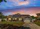 Charming single-story home at twilight with a well-manicured lawn, solar panels, and attached two-car garage at 6017 Brookhill Ct, Orlando, FL 32810