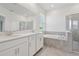 Bright bathroom featuring double sinks, white cabinetry, garden tub, and walk-in shower at 6139 Claystone Way, Mount Dora, FL 32757