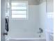 Bright bathroom featuring white tile, shower, tub, window, and neutral walls at 6203 Candlewood Ln, Orlando, FL 32809