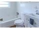 Bright bathroom with white tile, sink, toilet, tub, and wood-look floors at 6203 Candlewood Ln, Orlando, FL 32809