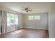Hardwood floor living room with a ceiling fan, large windows with patterned curtains, and neutral colored walls at 6203 Candlewood Ln, Orlando, FL 32809