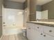 Bathroom with white cabinets, granite counters, and tiled tub surround at 6400 Raleigh St # 3015, Orlando, FL 32835