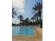 Large outdoor pool with palm trees, lounge chairs, and swimmers on a bright, sunny day at 7745 Somersworth Dr, Kissimmee, FL 34747