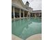 Outdoor pool surrounded by a building, featuring chairs and tables in a covered area at 7745 Somersworth Dr, Kissimmee, FL 34747