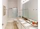 A full bathroom with double sinks, framed mirror, a shower with glass door and neutral tile flooring at 8851 Fallen Oak Dr, Davenport, FL 33896
