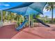 Outdoor playground featuring a colorful slide and climbing structures, shaded by a blue canopy and palm trees at 8989 Rhodes St, Kissimmee, FL 34747