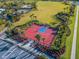 Aerial view of a vibrant red and blue basketball court, surrounded by palm trees in a well-maintained community at 1003 Nathan Ridge Rd, Clermont, FL 34715