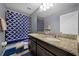 Bathroom featuring granite countertops, dual sinks, and stylish blue patterned shower curtain at 1003 Nathan Ridge Rd, Clermont, FL 34715