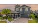 Elegant two-story home features a covered entry, neutral gray tones, lush landscaping, and a brick driveway at 1003 Nathan Ridge Rd, Clermont, FL 34715