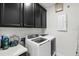 Functional laundry room boasts modern washer and dryer, paired with sleek, dark cabinetry for ample storage at 14639 Winter Stay Dr, Winter Garden, FL 34787