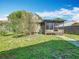 A view of the backyard featuring a screened-in patio and lush green lawn under a blue sky at 1511 New York Ave, St Cloud, FL 34769