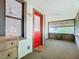 Enclosed porch with white wainscoting, a red door, and several windows providing natural light at 1511 New York Ave, St Cloud, FL 34769