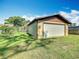 Exterior of a detached one-car garage featuring a new, bright white garage door and green lawn at 1511 New York Ave, St Cloud, FL 34769