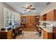 Spacious home office with custom wood shelving, two desks, and a ceiling fan at 162 Seville Chase Dr, Winter Springs, FL 32708