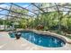 Backyard features a screened pool and spa surrounded by stone accents and lush landscaping at 162 Seville Chase Dr, Winter Springs, FL 32708