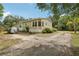 View of the side of the house with gravel driveway and mature trees at 2229 N 6Th St, Orlando, FL 32820