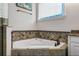 Elegant bathroom featuring a corner soaking tub with decorative tile surround and a bright window at 304 Muirfield Loop, Reunion, FL 34747