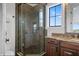 Elegant bathroom with a glass-enclosed shower, granite vanity, and a window offering natural light and scenic views at 304 Muirfield Loop, Reunion, FL 34747