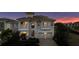 Elegant two-story home featuring a tile roof, balconies, and a paved driveway against a colorful twilight sky at 304 Muirfield Loop, Reunion, FL 34747
