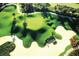 Scenic aerial view of a meticulously maintained golf course featuring sand traps, lush greens, and palm trees at 304 Muirfield Loop, Reunion, FL 34747