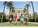 Happy golfers walking towards clubhouse, with palm trees and immaculate lawns, representing resort-style living at 304 Muirfield Loop, Reunion, FL 34747