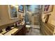 A well lit bathroom featuring a glass door shower, stone flooring and a dark wood vanity at 3338 Robert Trent Jones Dr # 30704, Orlando, FL 32835