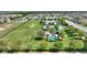 An aerial view showing a community park that features a playground, sports field, and a swimming pool, all surrounded by green lawns at 372 Willet St, Haines City, FL 33844