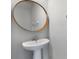 Modern pedestal sink with a round mirror and white fixtures at 372 Willet St, Haines City, FL 33844
