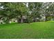 Expansive backyard with lush green lawn, mature trees, and screened-in porch for outdoor relaxation and entertainment at 3843 Beacon Ridge Way, Clermont, FL 34711