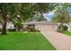 Charming home featuring a lush lawn, mature trees, and a two-car garage at 3843 Beacon Ridge Way, Clermont, FL 34711