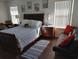 Comfortable main bedroom featuring a queen-sized bed, soft lighting, and a seating area at 4031 Calabria Avenue, Davenport, FL 33897
