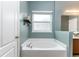 Inviting soaking tub situated beneath a window and next to vanity in this relaxing light blue toned bathroom at 420 Tulipwood Ln, Chuluota, FL 32766